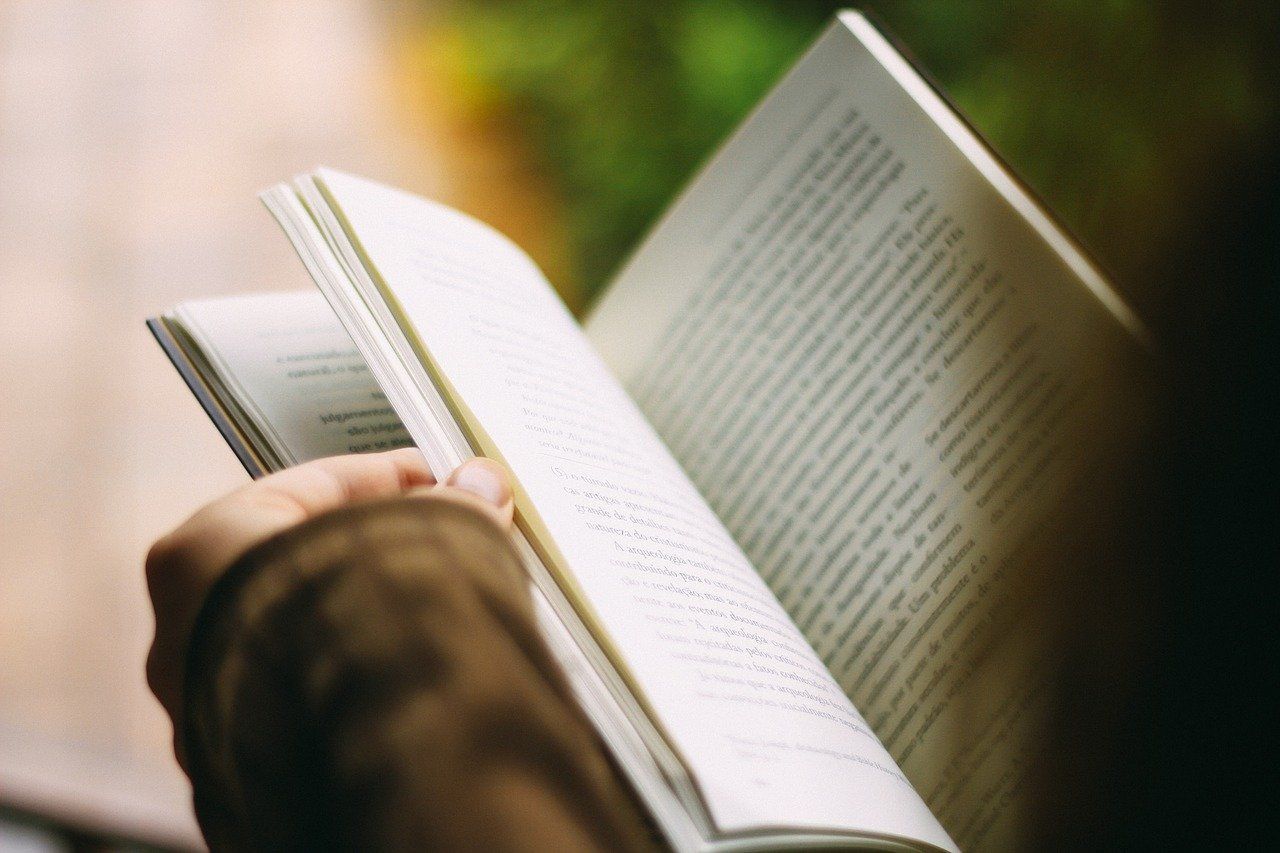 Bücherflohmarkt Ein Mann hält ein Buch aufgeschlagen in der Hand und liest darin