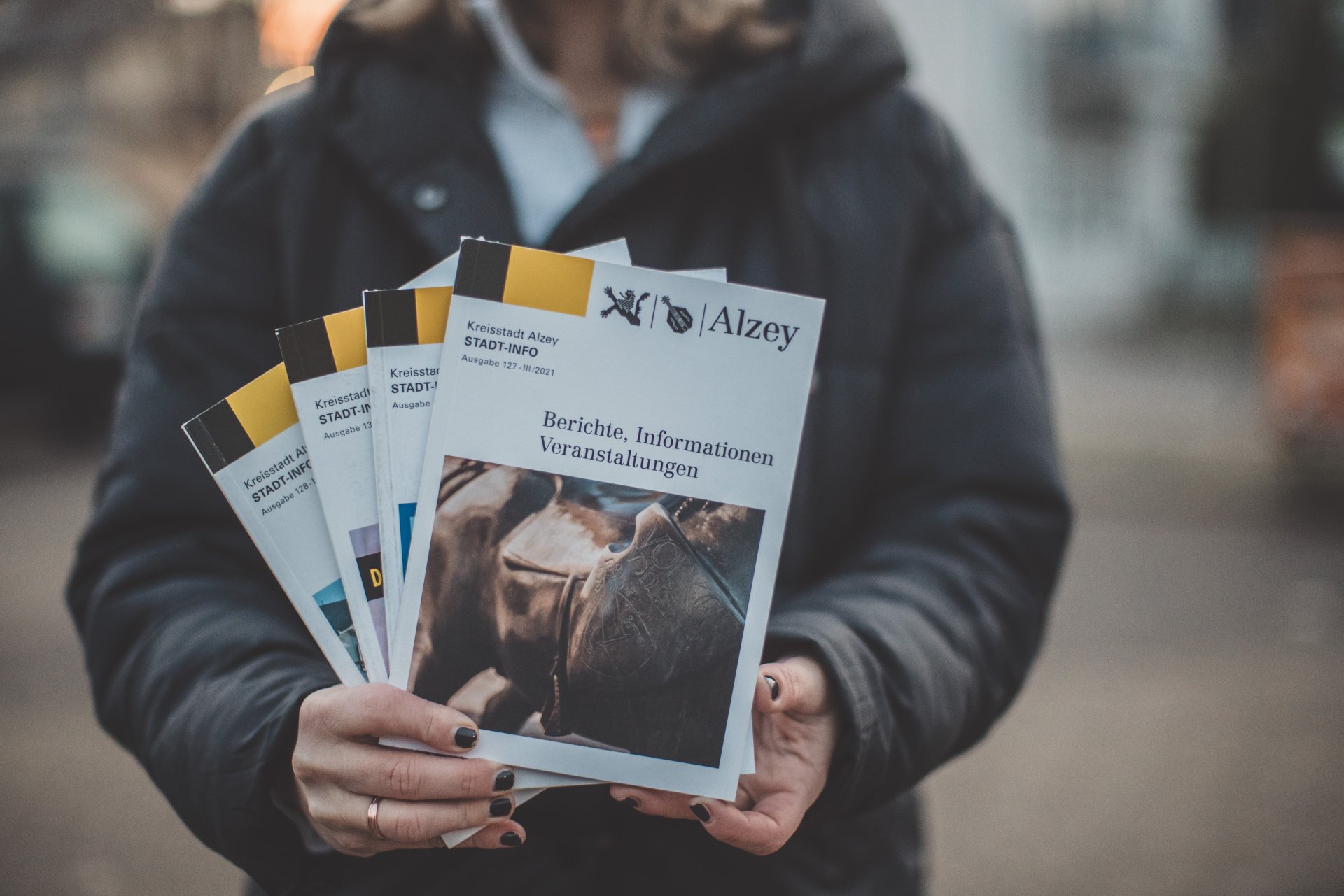 Eine Person hält mehrere Stadt-Infos in die Kamera