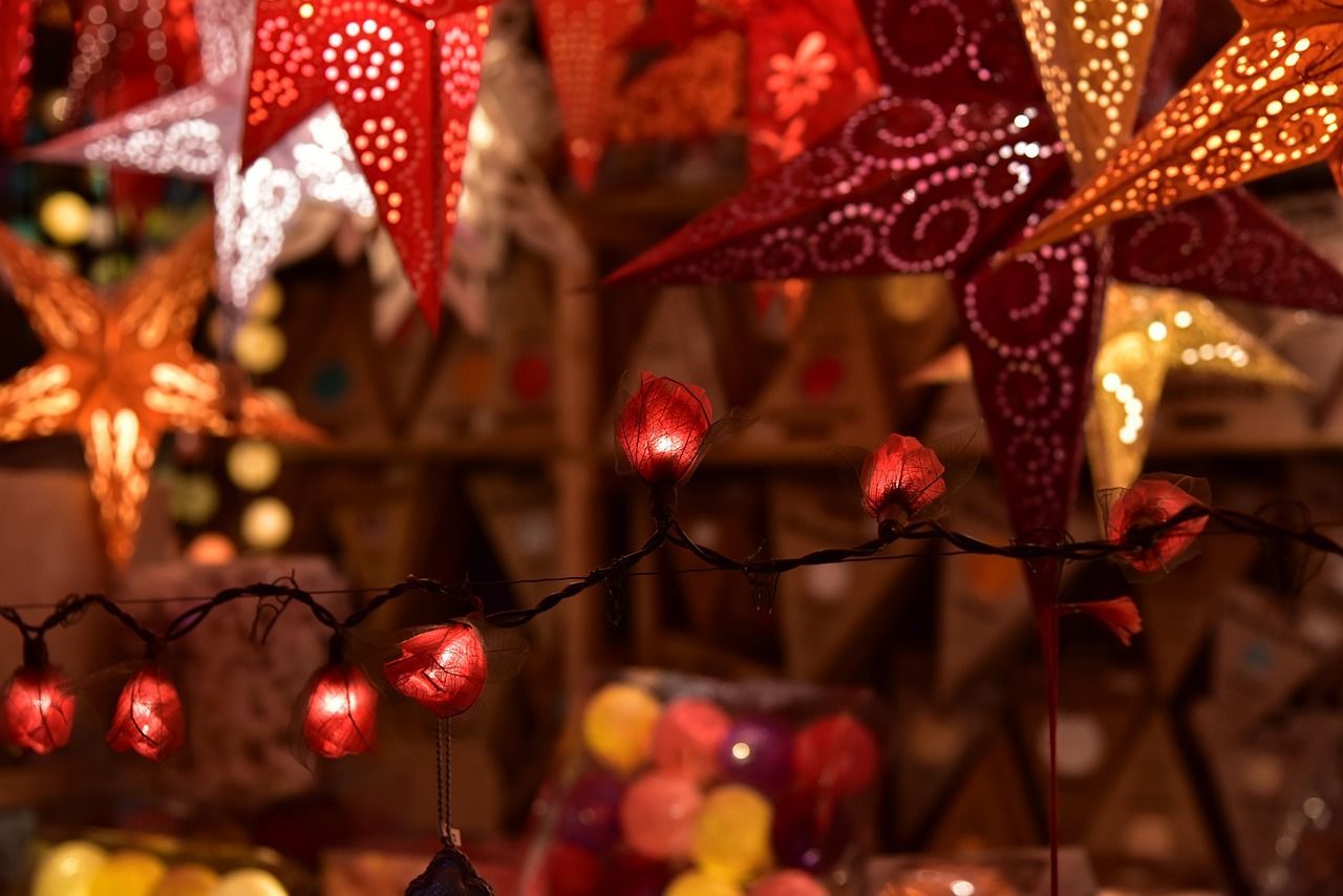 Durch das ganze Bild zieht sich eine weihnachtliche Lichterkette mit Glühlampen und Sternen in den Farben rot und orange.