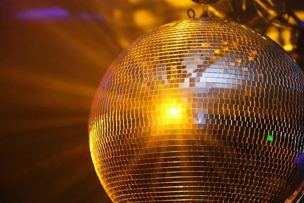 Mann sieht eine Discokugel die in Goldenem Licht erstrahlt.