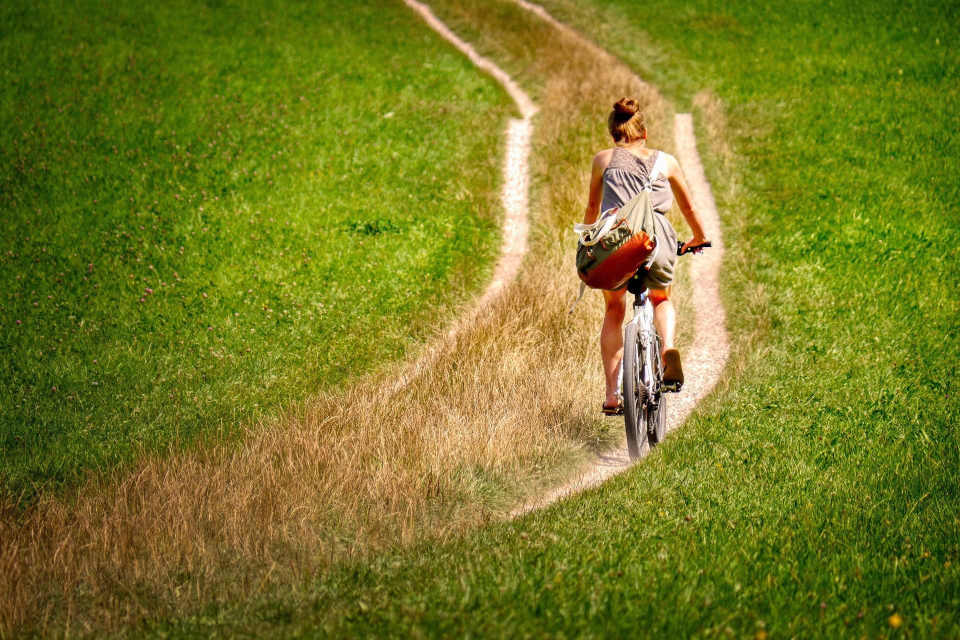 eine Frau fährt Fahrrad im Feld auf dem Feldweg