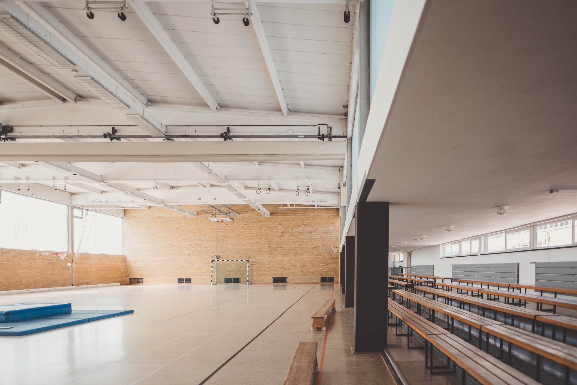 Turnhalle mit einer Sitztribüne rechts im Bild und einer blauen Turnmatte in der Mitte der Halle.
