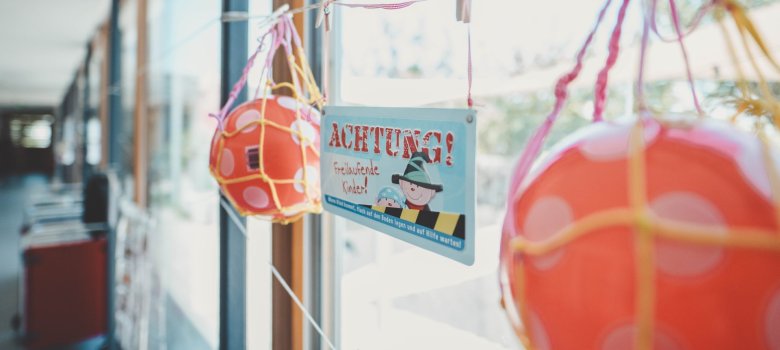 2 Bälle im Netz mit dem Schild "Achtung freilaufende Kinder"