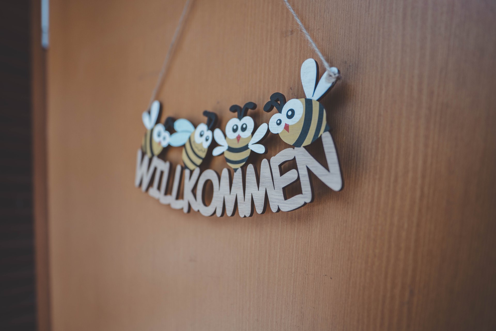 ein hängendes Schild mit Bienen und dem Wort Willkommen an der Tür