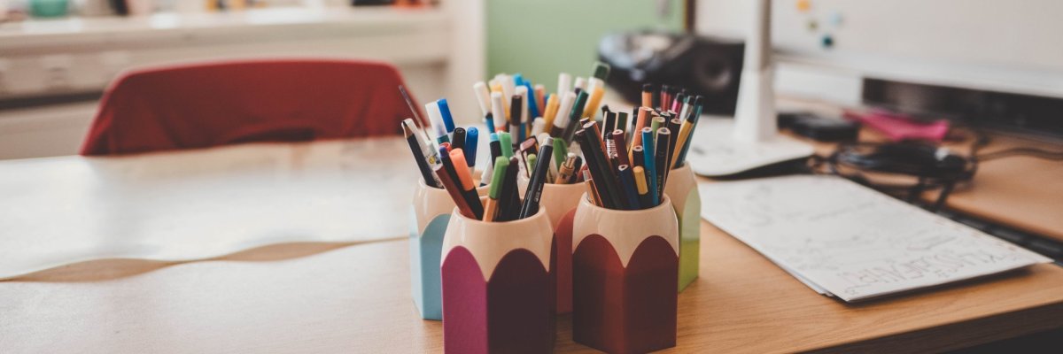 Grundschulen ein Schreibtisch mit vielen Stiften in Behältern, die aussehen wie Stifte