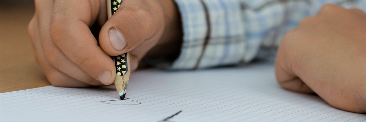 Kind schreibt mti einem Stift in ein Heft