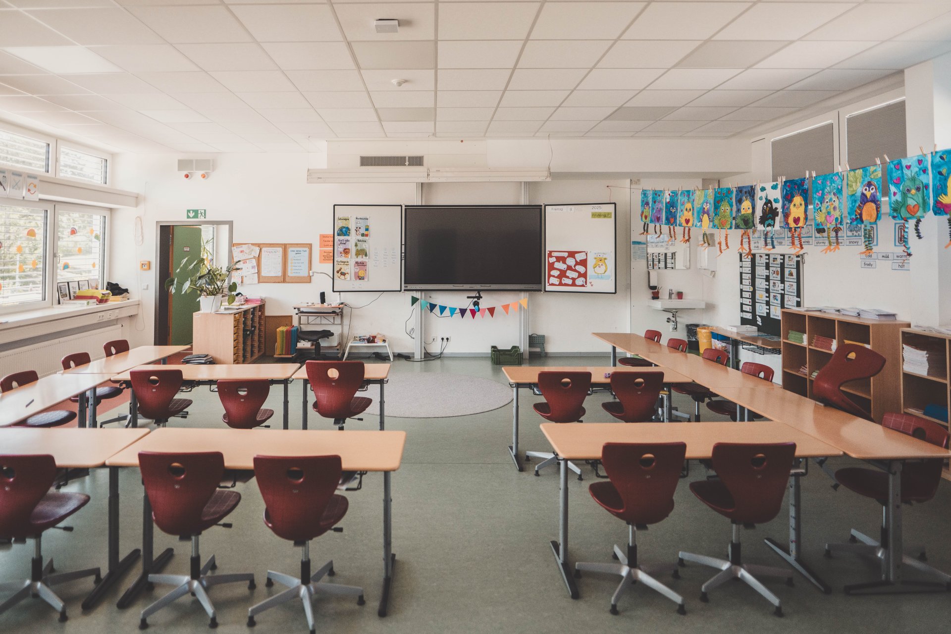 Ein Klassenraum, in dem rote Stühle an den Schultischen stehen.