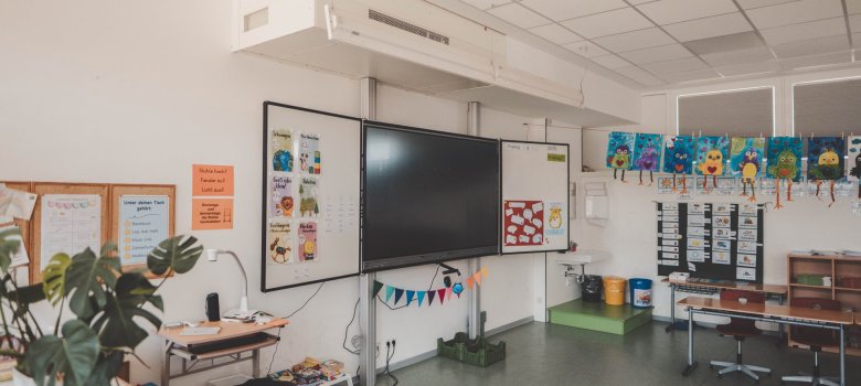 Eine digitale Tafel in einem bunt eingerichteten Klassenraum.