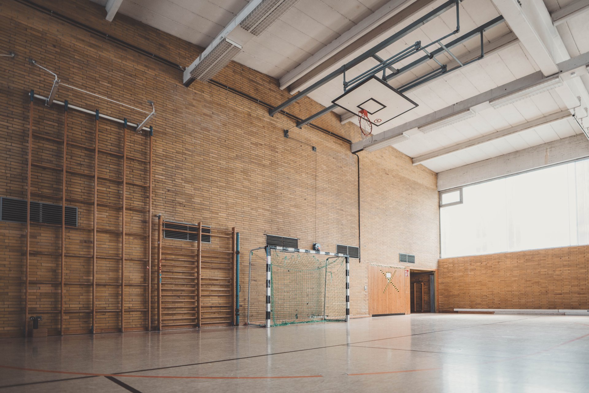 Eine Turnhalle mit einem Handballtor und einer hohen, hölzernen Kletterwand.