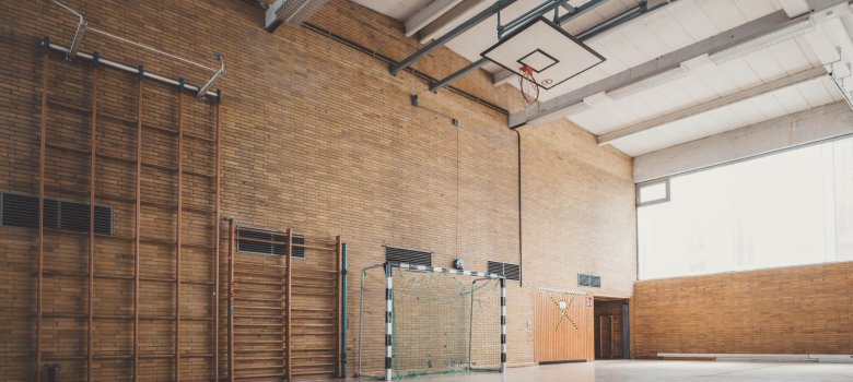 Eine Turnhalle mit einem Handballtor und einer hohen, hölzernen Kletterwand.