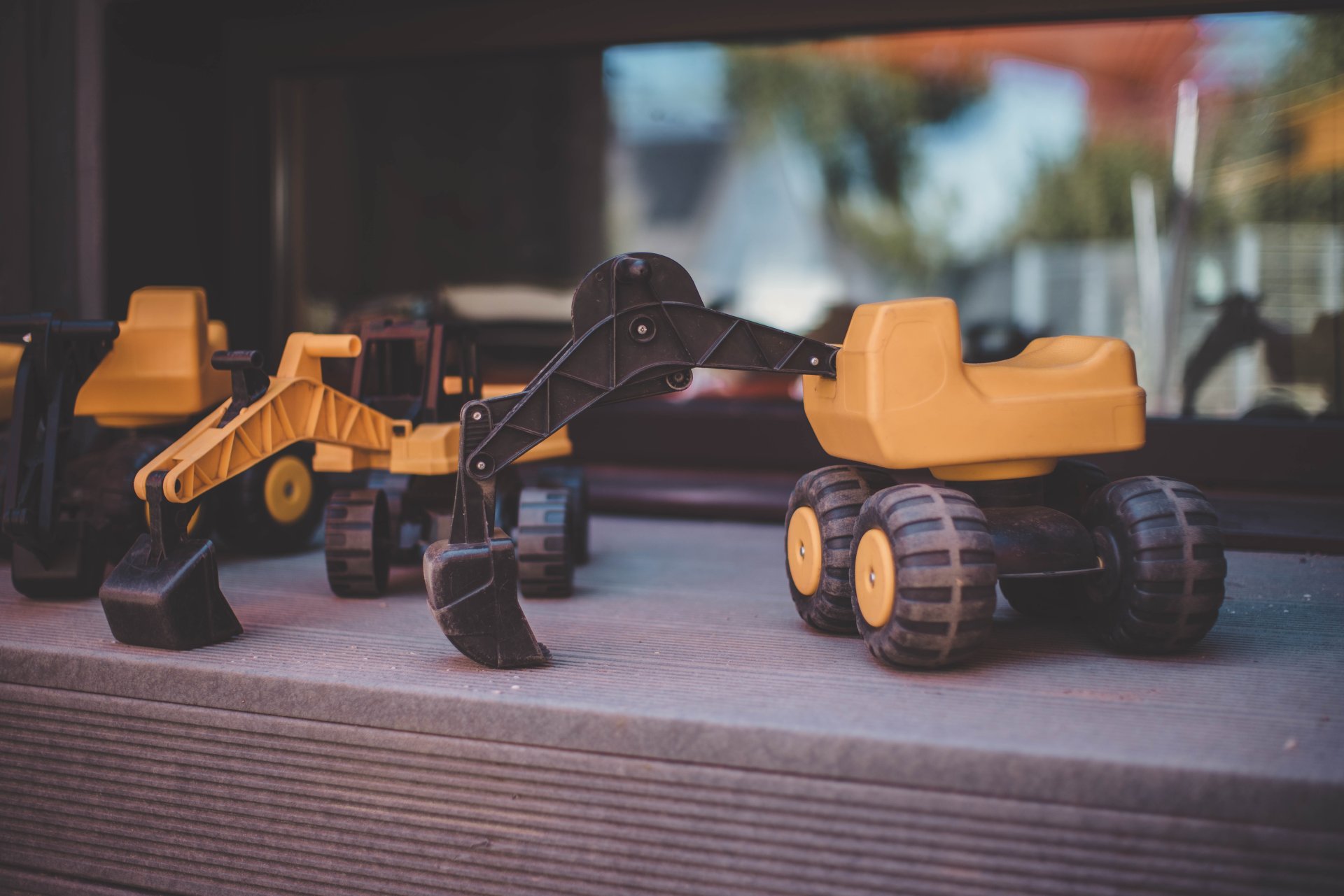 Kita Haus der Klänge Drei kleine gelbe Spielzeugbagger stehen außen auf einer Fensterbank.