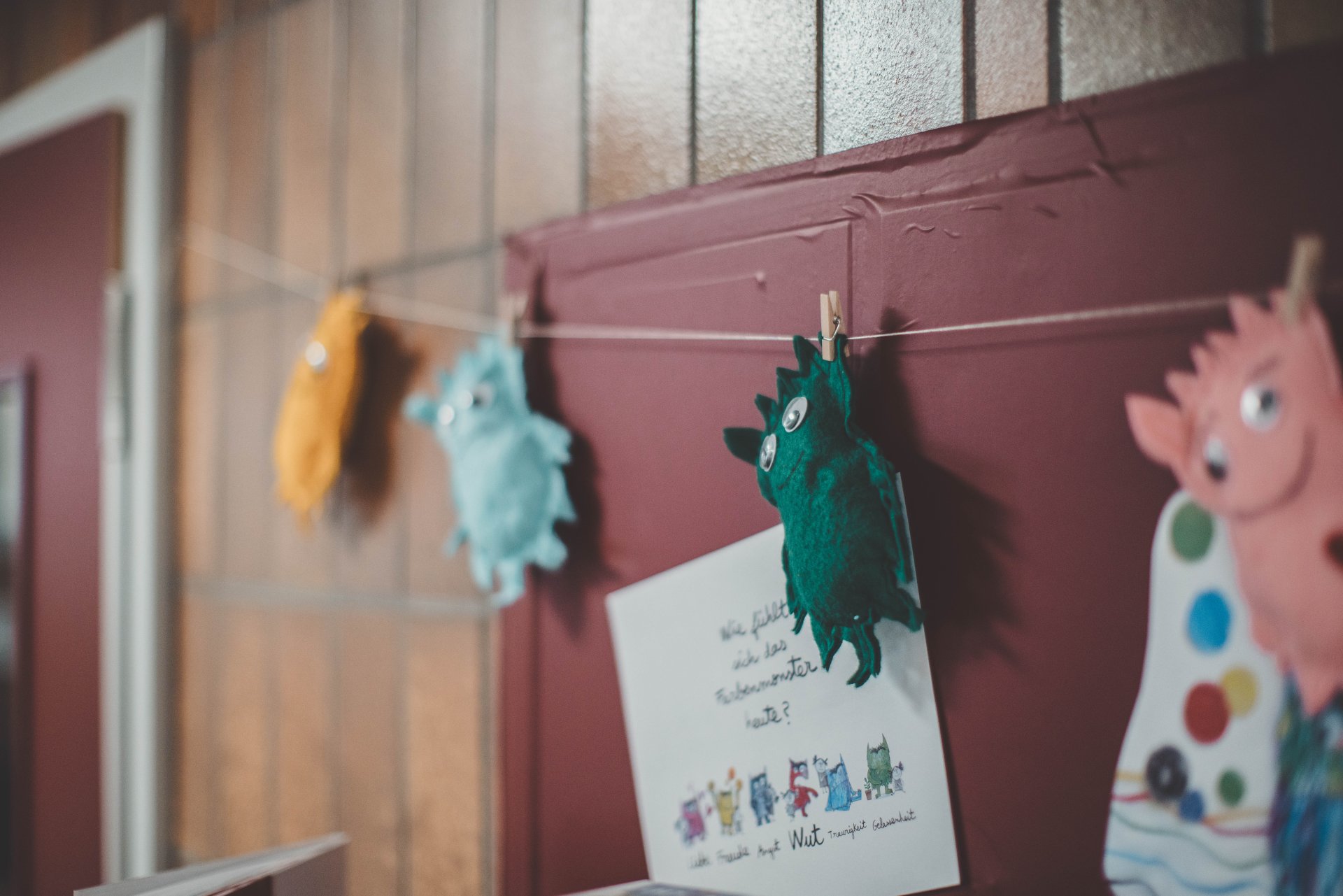 Kita Walter Zuber Stoffmonster, die in einer Kita an einer Leine zur Dekoration hängen