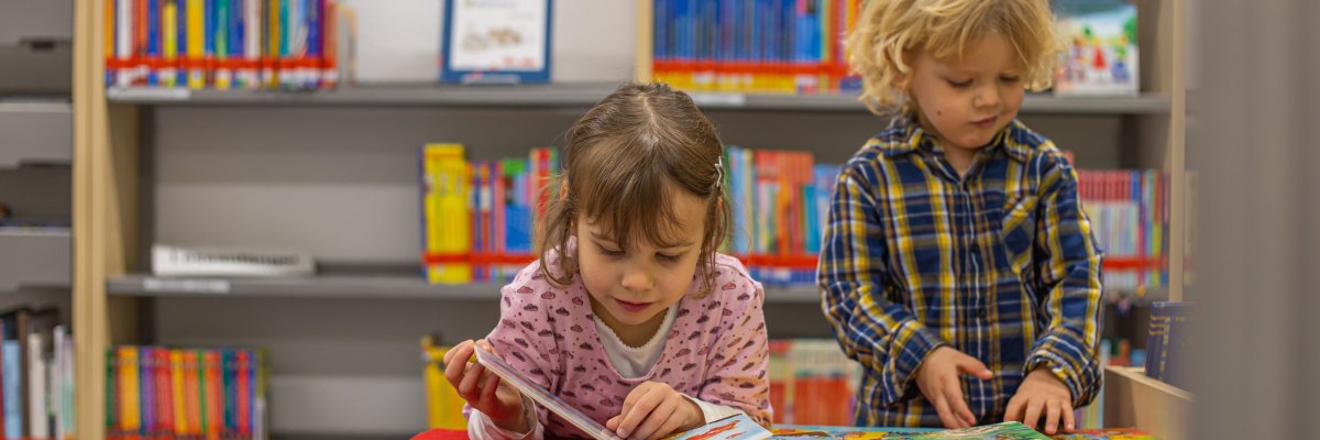 Zwei Kinder lesen gemeinsam in der Bücherei
