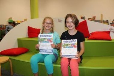 Kinder halten ihre Urkunde für den Lesesommer