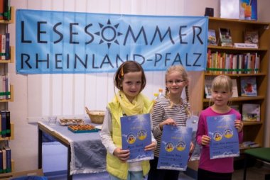 Kinder halten ihre Urkunde für den Lesesommer