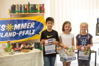 Kinder halten ihre Urkunde für den Lesesommer