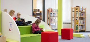 Kinder nutzen die Sitzgelegenheit in der Bücherei um zu lesen