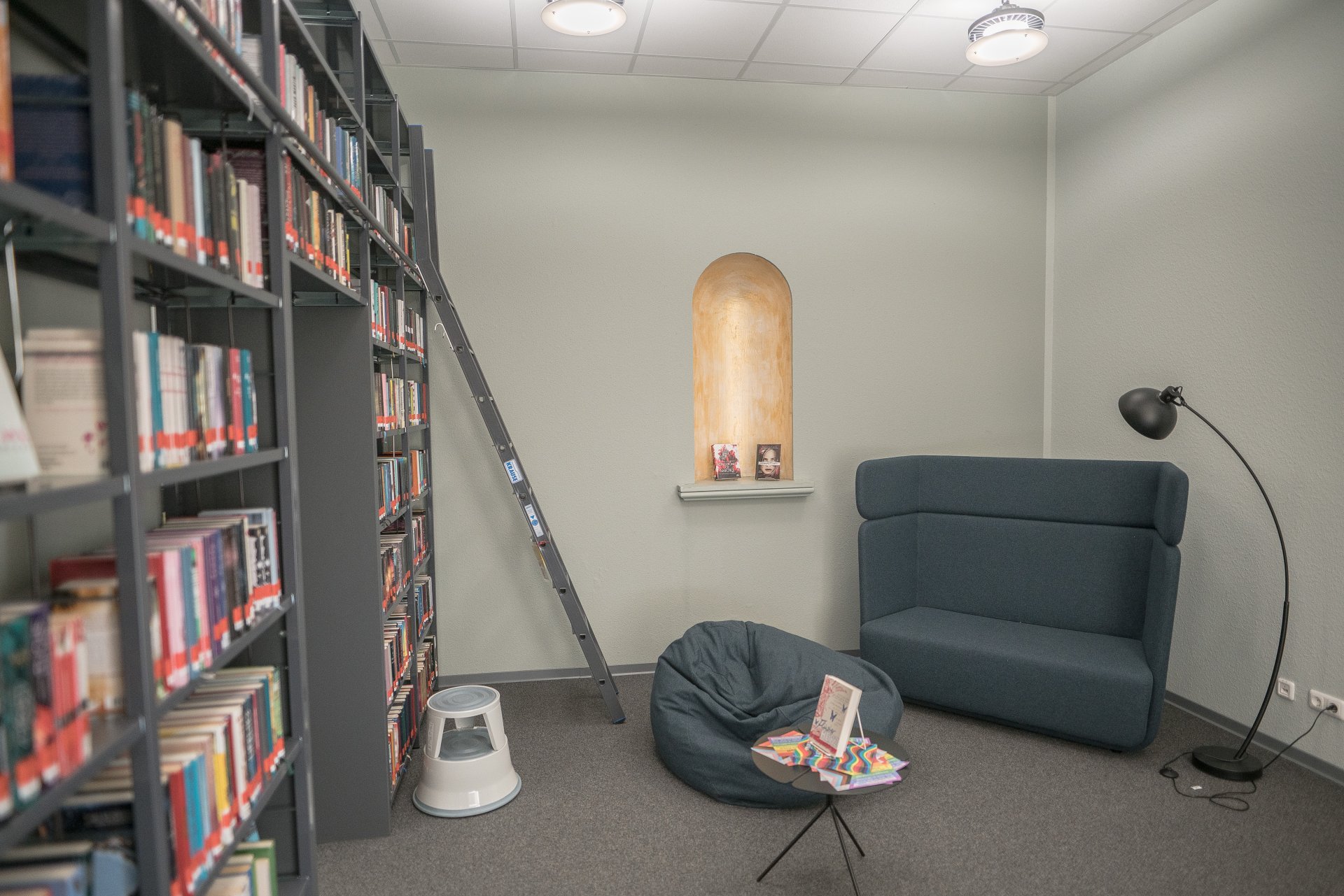 eine Leseecke mit Sofa und Sitzkissen in der Stadtbücherei Alzey neben einem Bücherregal