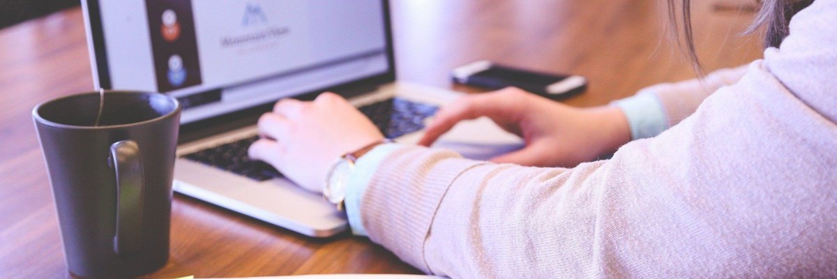 Person schreibt mit ihrem Laptop
