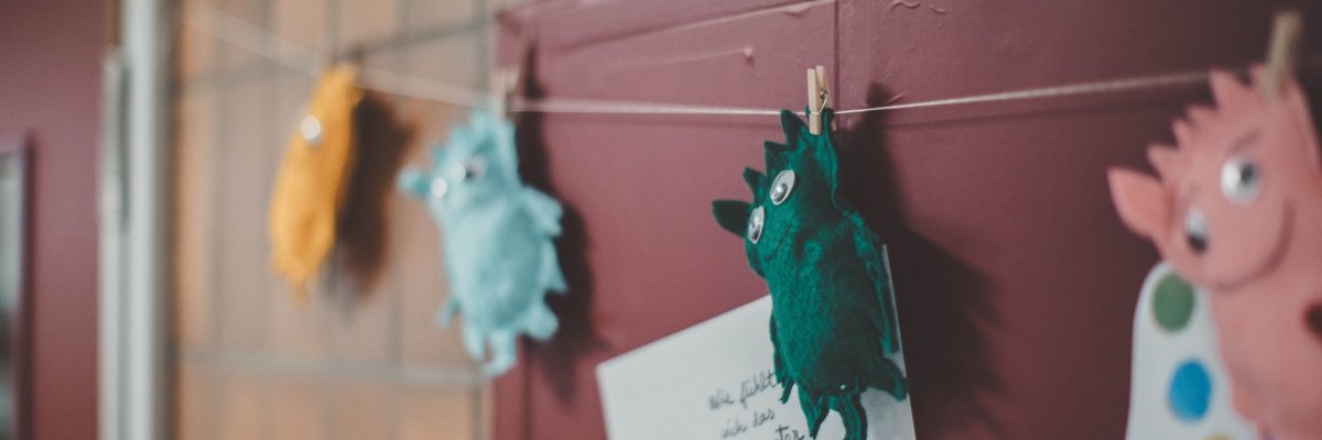 Bunte Stoffmonster, die in einem Kindergarten oder einer Schule an einer Leine hängen.