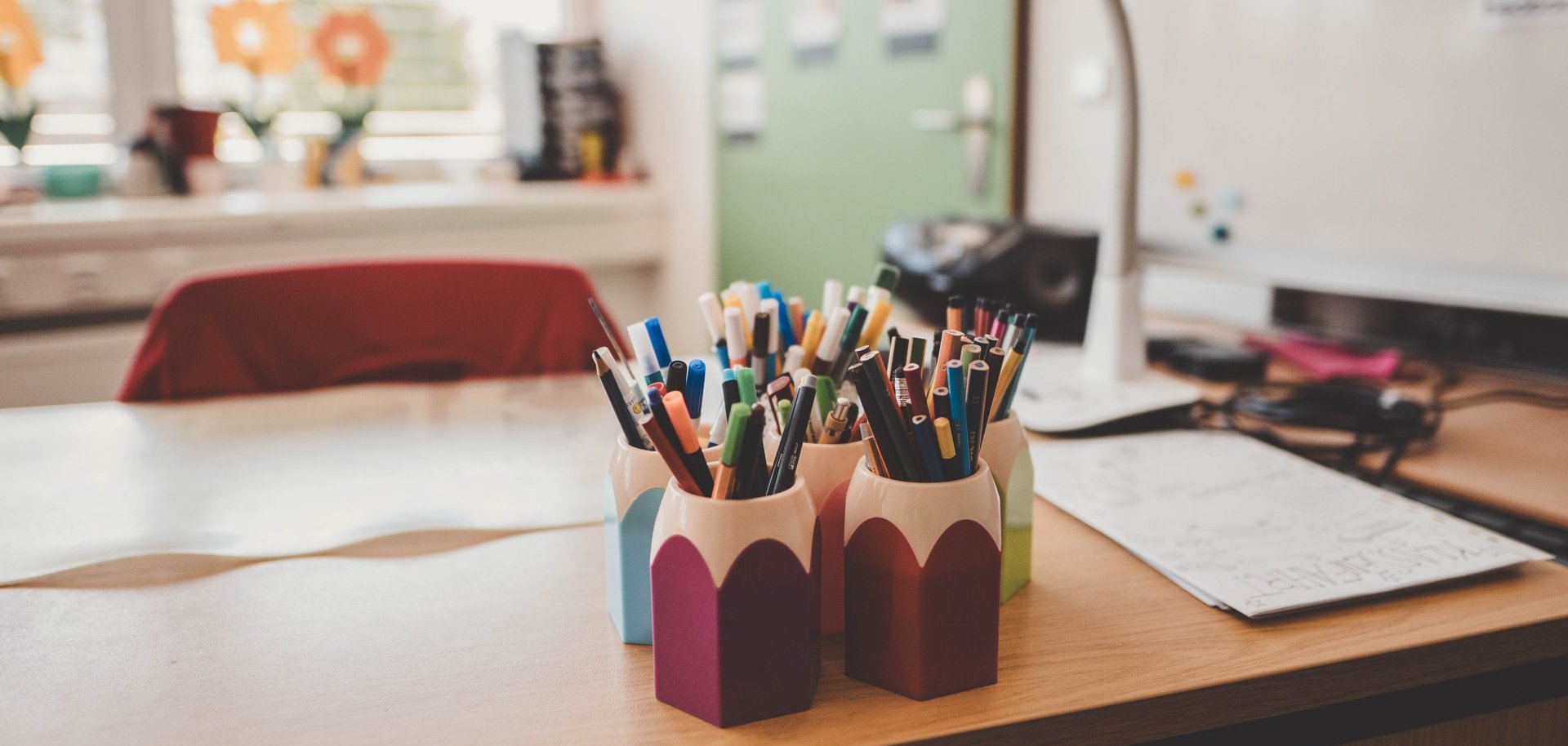 Grundschulen ein Schreibtisch mit vielen Stiften in Behältern, die aussehen wie Stifte