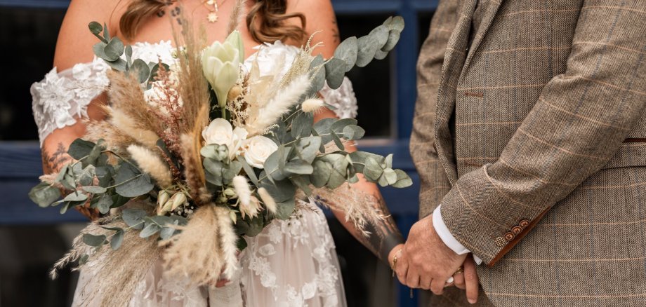 Trauungen in Alzey Brautpaar nebeneinander in Anzug und Kleid mit Brautstrauß in der Hand