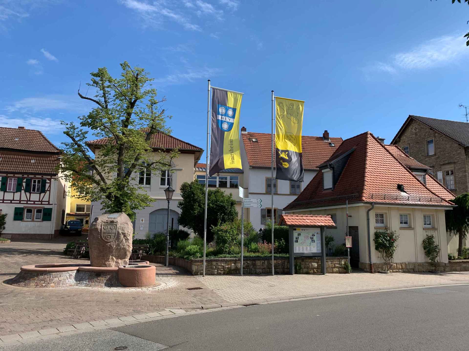 Der Dorfplatz in Heimersheim mit gehissten Flaggen in gelb-schwarz und dem Stadtlogo.