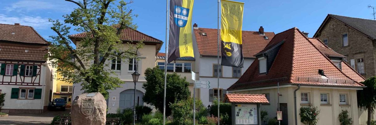 Der Dorfplatz in Heimersheim mit gehissten Flaggen in gelb-schwarz und dem Stadtlogo.