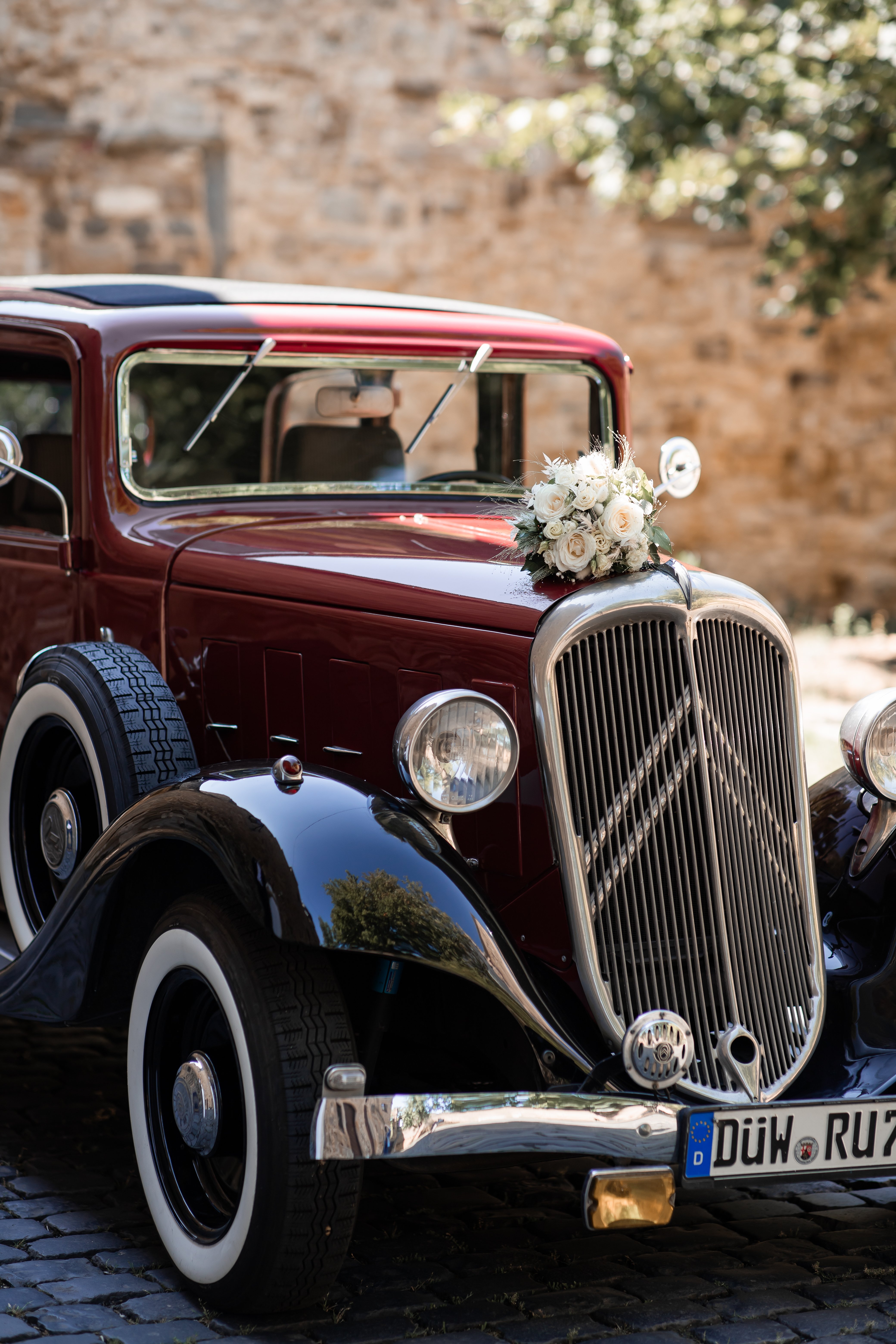 Hochzeitsoldtimer mit Brautbukett auf der Motorhaube