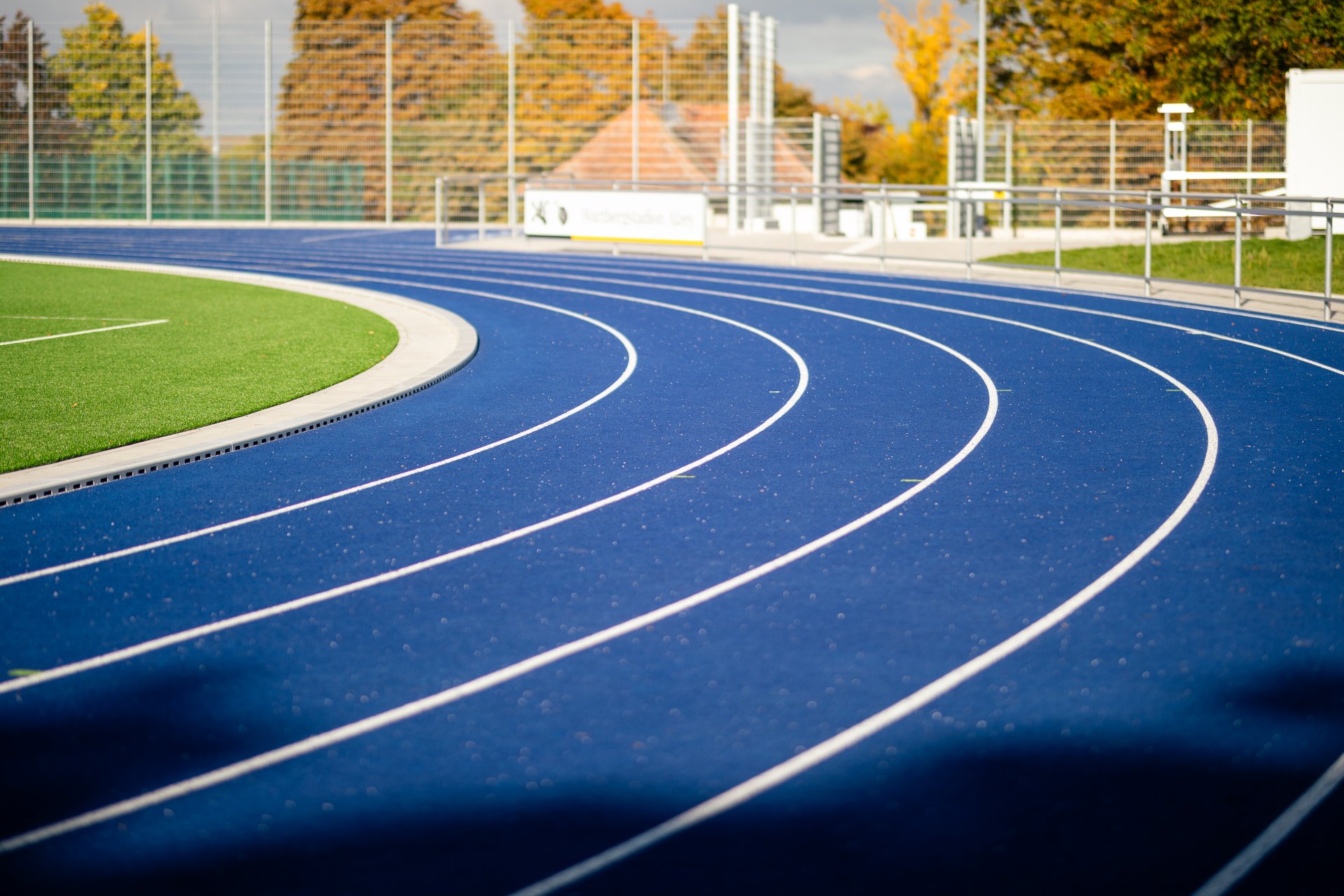 Auf dem Bild ist der neue Sportplatz dargestellt. Links sieht man ein bisschen von dem grünen Rasenplatz und rechts nebendran befindet sich die neue blaue Tartanbahn.