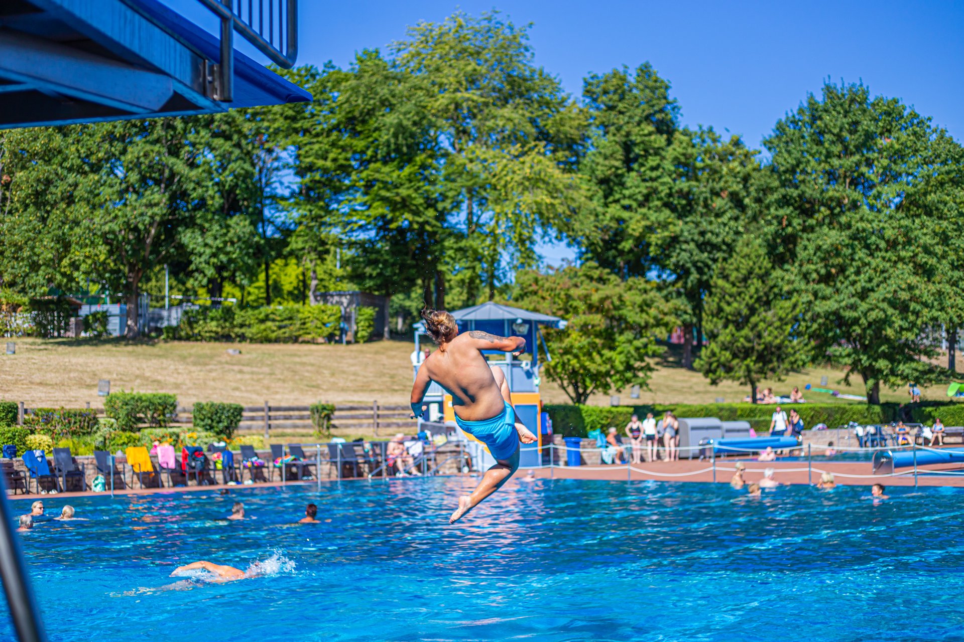 Schwimmerbecken in Alzey, in das ein Mann vom Drei-Meter-Brett springt.