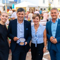Vier Personen stehen nebeneinander und lachen gemeinsam in die Kamera.