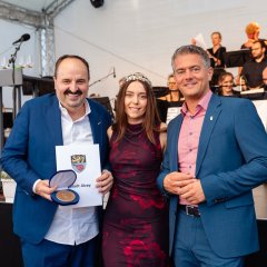 Johann Lafer, Weinkönigin Nicole und Bürgermeister Steffen Jung stehen nebeneinander und lachen in die Kamera.