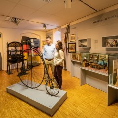 Besucher im Alzeyer Museum, die sich ein Hochrad anschauen.