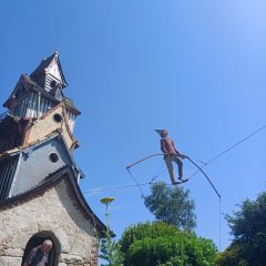 Zwergfigur auf einem Seil, in der Luft.
