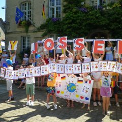 Kinder halten gebastelte Schilder hoch.