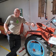 ein Mann lehnt sich an einen alten Traktor