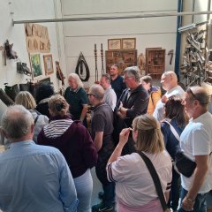 mehrere Personen stehen in einem Museum mit alten, landwirtschaftlichen Gegenständen