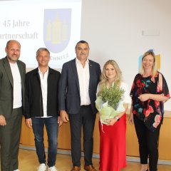 fünf Personen stehen nebeneinander und lachen in die Kamera, eine Person hält einen Olivenbaum in der Hand