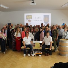 eine Gruppe von Personen steht in einem Saal vor einem Beamer, auf dem abgebildet ist: