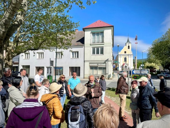 eine Gruppe von Personen steht um einen älteren Herrn herum, der grade etwas erzählt