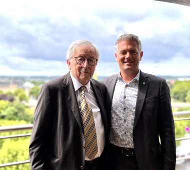 zwei Männer in Anzug stehen vor der Kamera und lachen in diese. Rechts steht Bürgermeister Steffen Jung, links von ihm der diesjährige Weinkulturpreisträger Jean-Claude Juncker