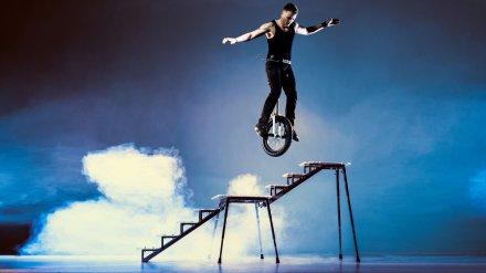 Ein Mann balanciert auf einem Einrad auf der Treppe