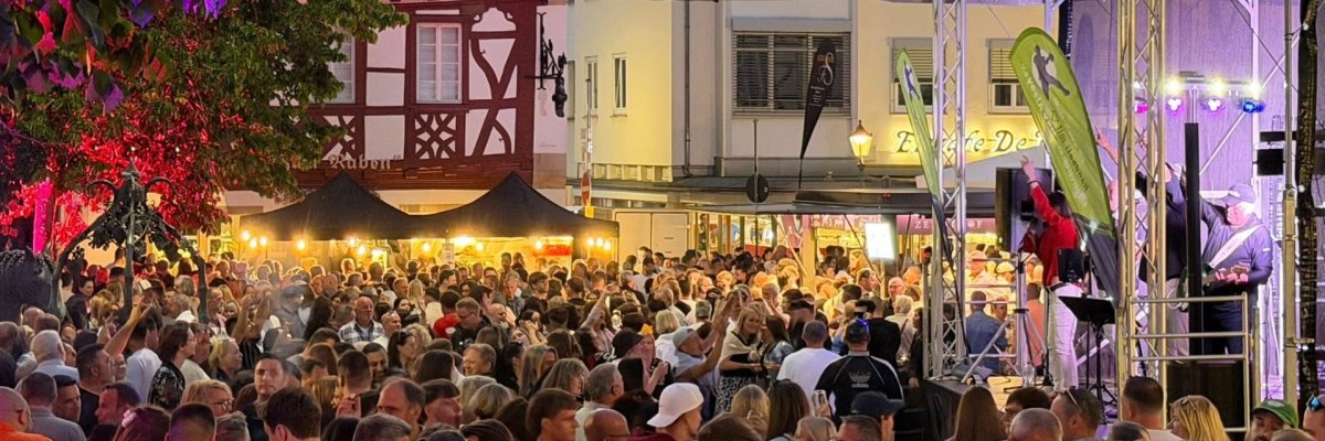 auf dem Alzeyer Roßmarkt stehen viele Menschen vor einer Bühne, viele von Ihnen halten ein Glas Wein in der Hand