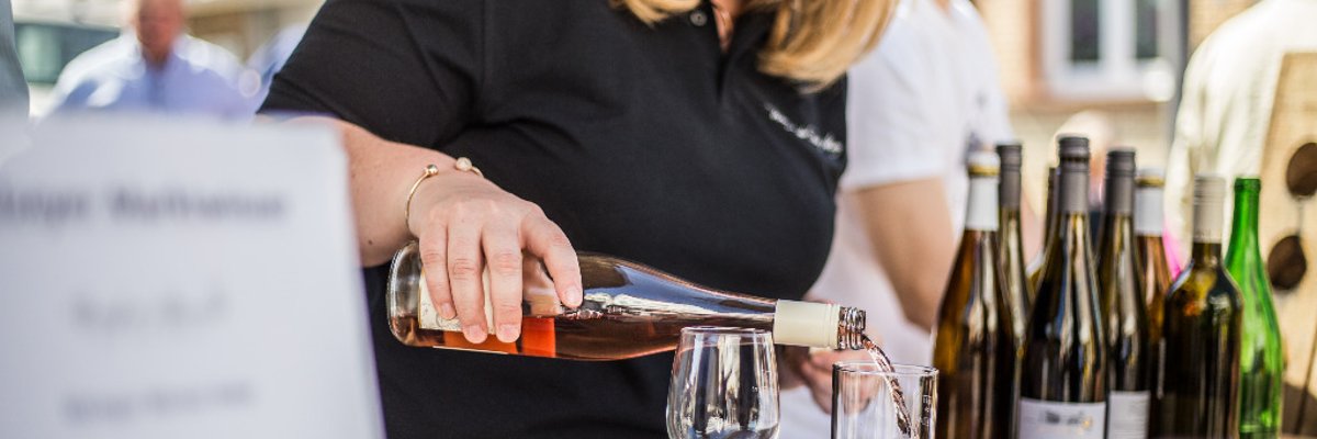 Markfrühstück auf dem Alzeyer Wochenmarkt Person schenkt Wein aus