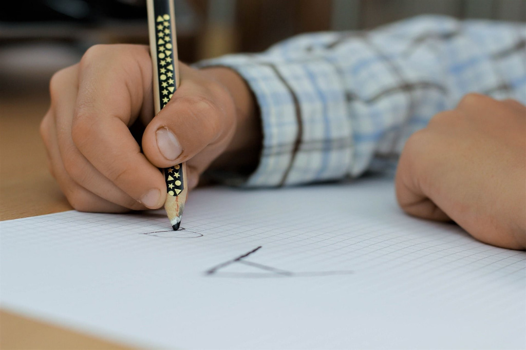 Kind schreibt mit einem Stift in ein Heft