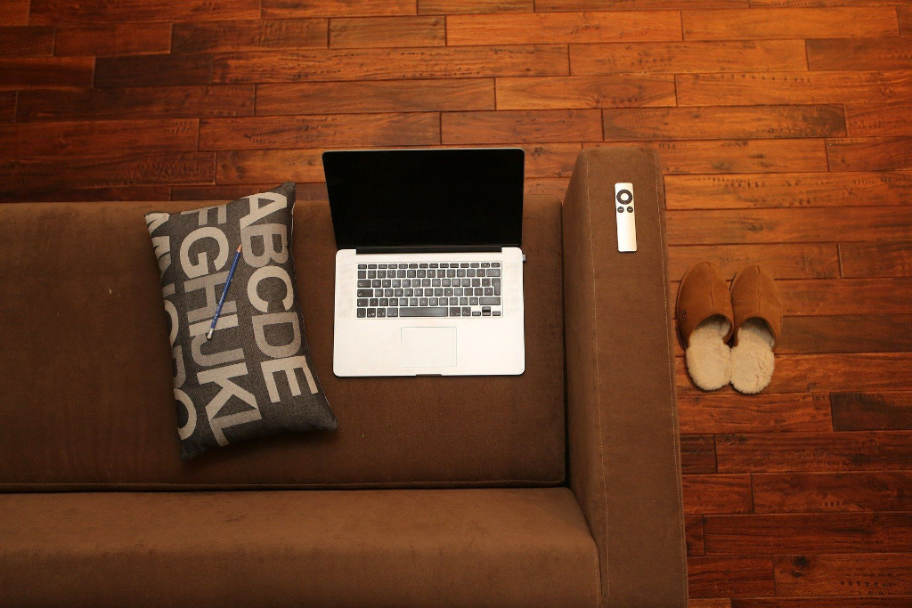 Laptop auf der Couch mit Fernbedienung 