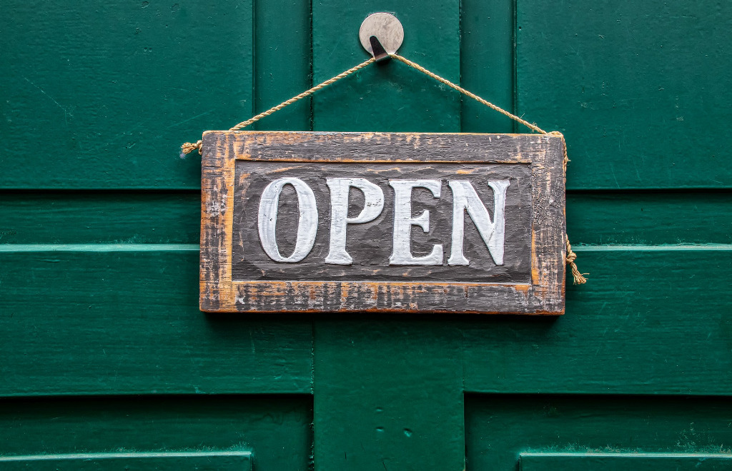 "Open"-Schild an einer grünen Tür