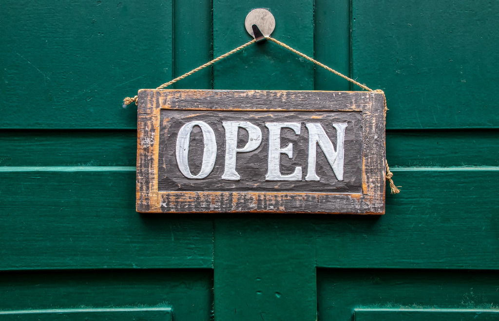 "Open" Schild an einer grünen Tür