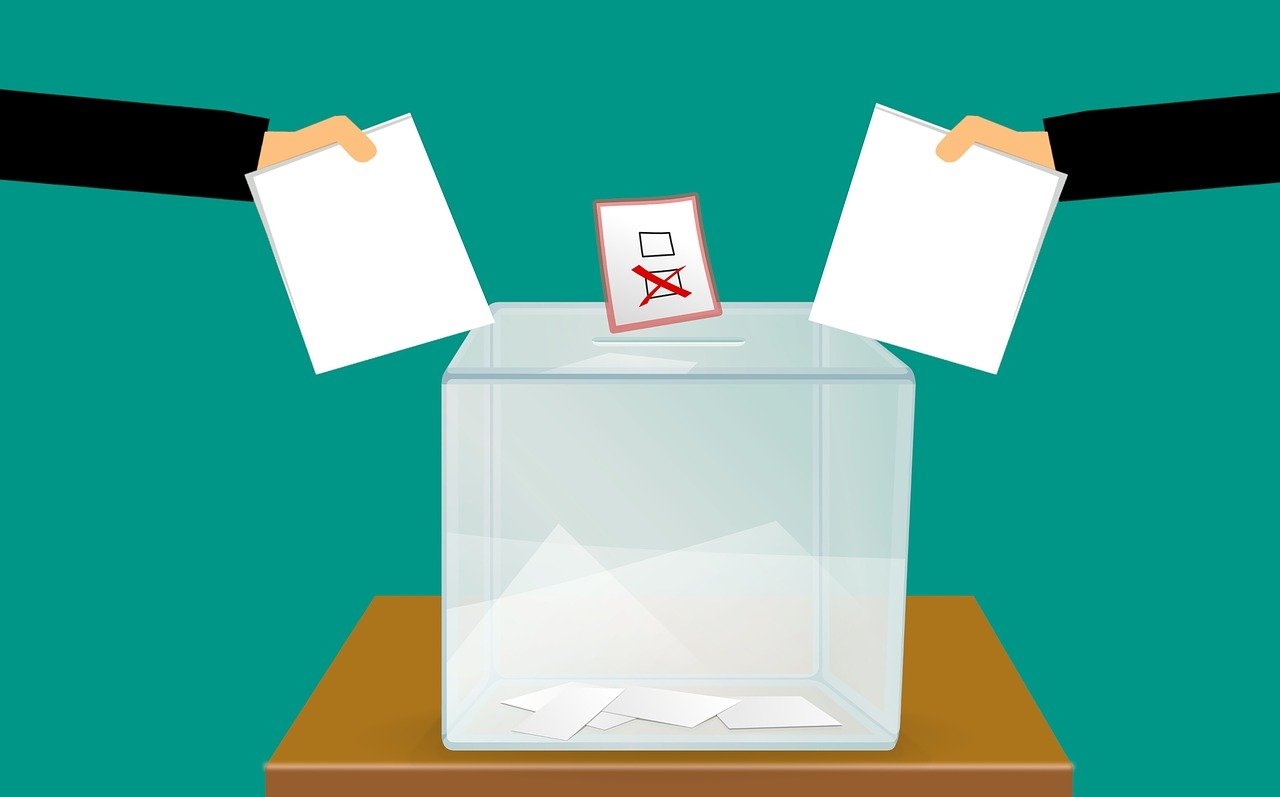 Personen werden Wahlzettel in eine Urne